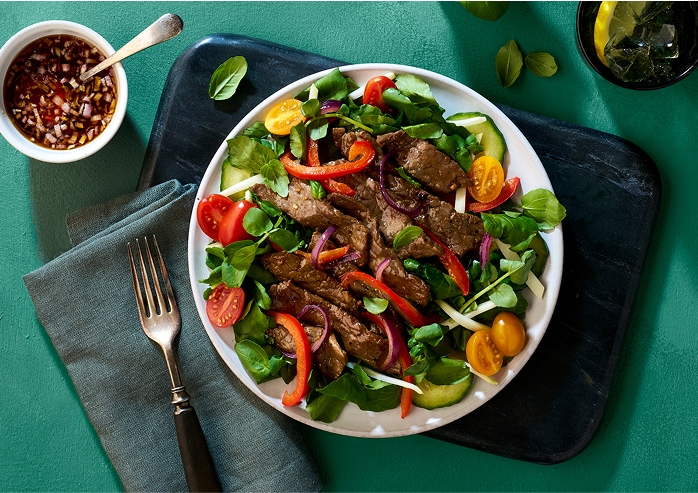 Delicious beef salad with fresh greens, tomatoes, onions, and a tangy dressing