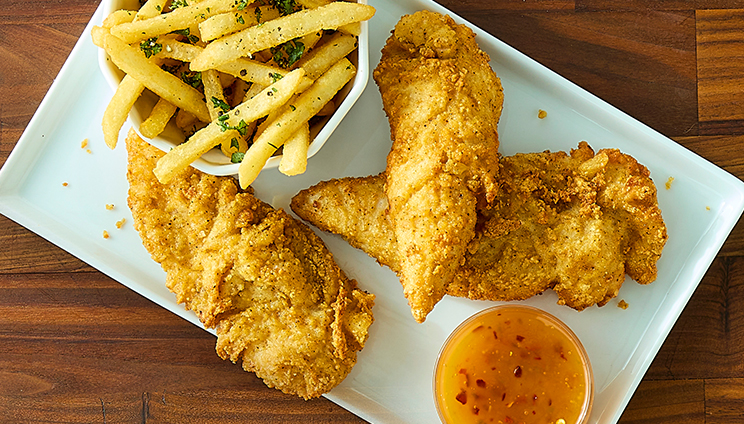 A plate of chicken tenders, seasoned fries, and a sweet chili dipping sauce