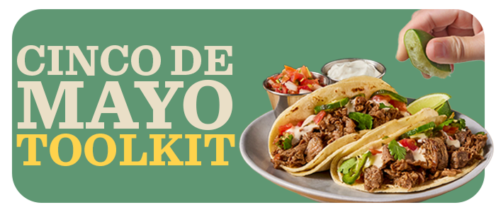 A hand squeezing fresh lime on two sliced beef tacos plated with sides of sour cream and Pico de Gallo