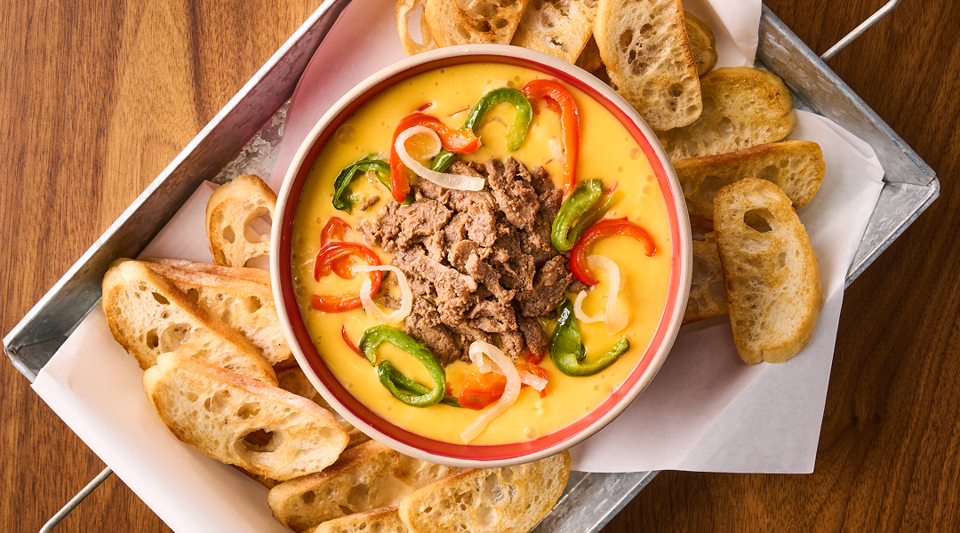 A dip with peppers and meant in it with a side of bread 