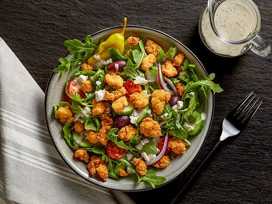 Lightly breaded Tyson® Mini Chicken Bites on a classic Mediterranean salad. 