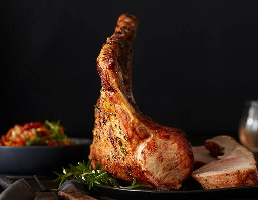 Pork tomahawk rack on top of rosemary on a plate