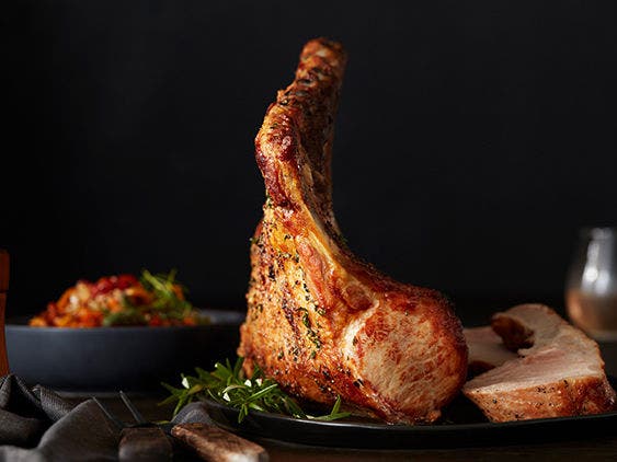 Pork tomahawk rack on top of rosemary on a plate.  