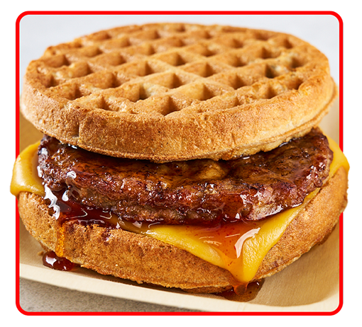 A sausage patty with cheese and syrup sandwiched between two small waffles  