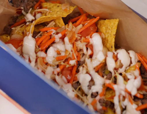 Chicken crumbles over corn tortillas topped with tomatoes, shredded cabbage, cheese sauce and sour cream 