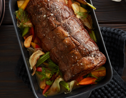 Braised chuck roast on a pan with onions, carrots and celery