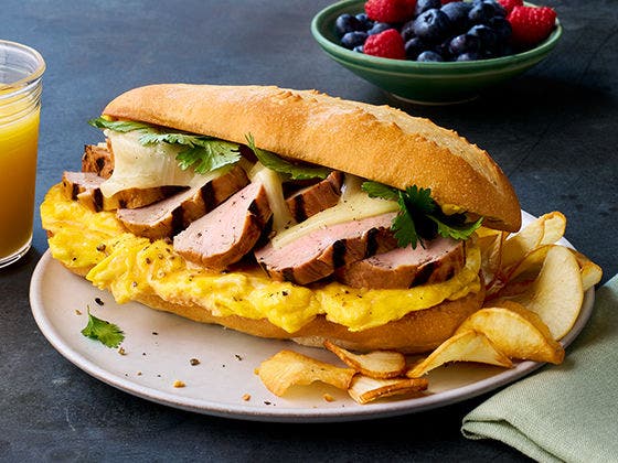 Slices of pork tenderloin and folded eggs on a French roll with Swiss cheese