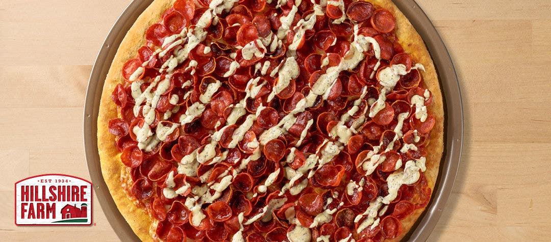 pepperoni pizza with a zig zag drizzle of ranch sauce over the top 