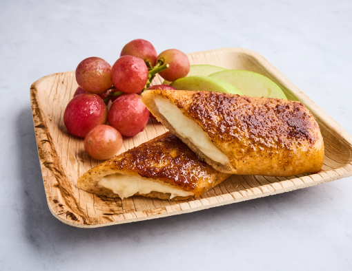 Mozzarella stuffed breadsticks halved served on a plate with grapes and apples 