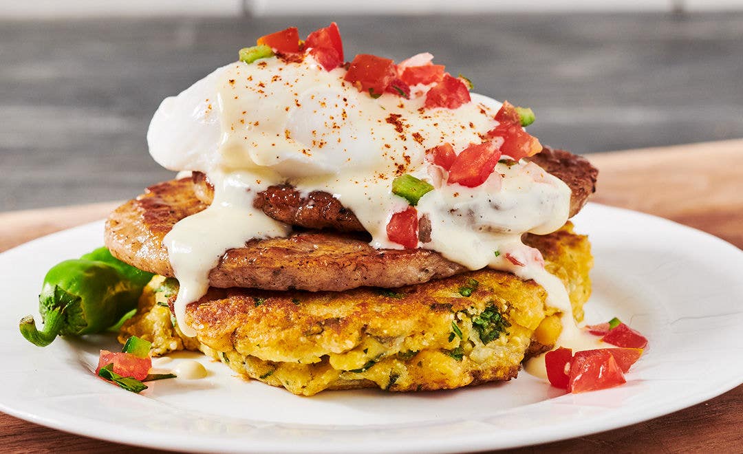 Johnny Cakes topped with a sausage pattie, poached egg and hollandaise sauce with a jalapeño on the side