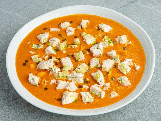 Large bowl of creamy red pepper bisque with bits of diced chicken breast meat