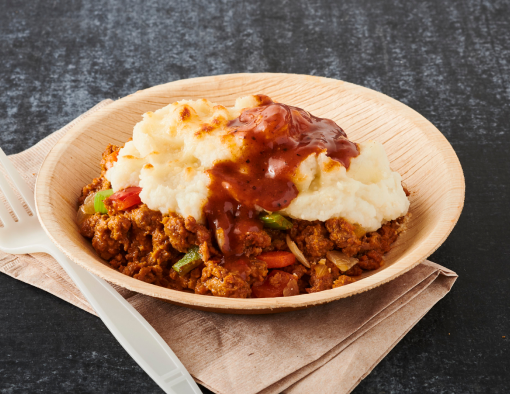 Seasoned chicken crumbles in a bowl topped with cauliflower mashed potatoes, carrots, onions, peppers, celery and sauce 