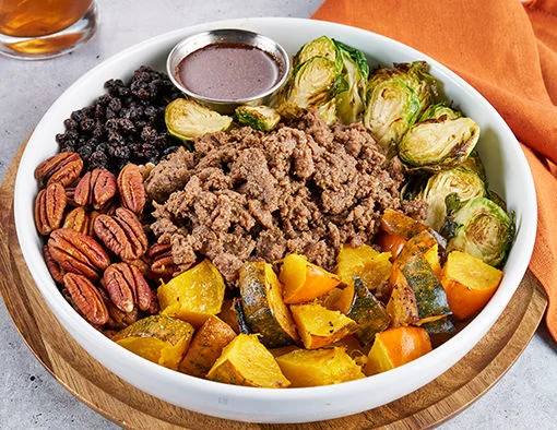 Crispy charred Brussels sprouts topped with maple-pepper glazed sliced beef steak, roasted acorn squash, toasted pecans, and black currants