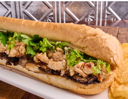 Chicken sandwich with black trumpet mushrooms, marsala vinaigrette on a hoagie roll, on a white plate