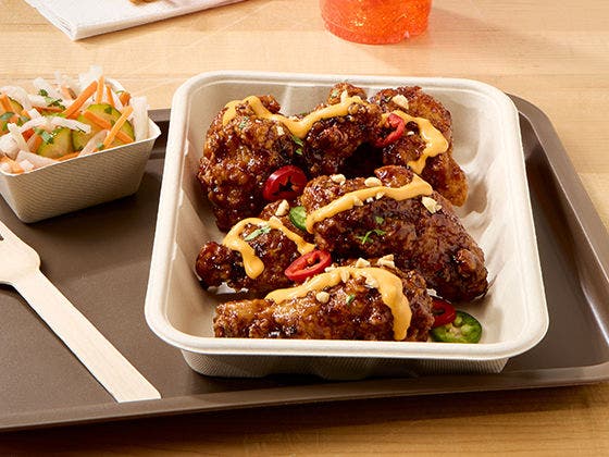 Tray of fried wings in hoisin sauce, topped with peanuts, Fresno peppers, sriracha mayo, and pickled salad