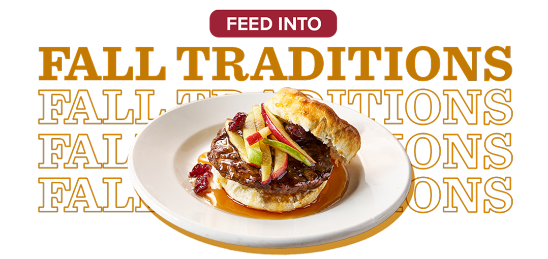 A white plate holding a pork sausage patty on a biscuit covered in syrup and topped with julienned apples and cranberries 