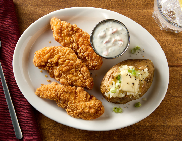 Gluten free chicken strips with sauce and a baked potato 