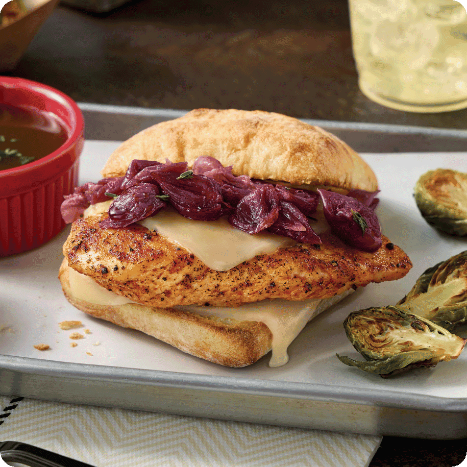 chicken sandwich with melted cheese and tender cooked onions on ciabatta roll with a side of au jus and Brussels sprouts 