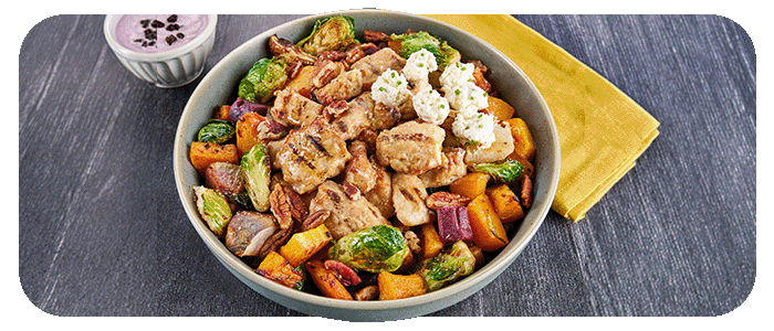 A bowl of roasted vegetables, Brussels sprouts, chicken chunks, cheese and whole pecans