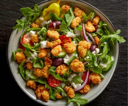 Lightly breaded Tyson® Mini Chicken Bites on a classic Mediterranean salad. 