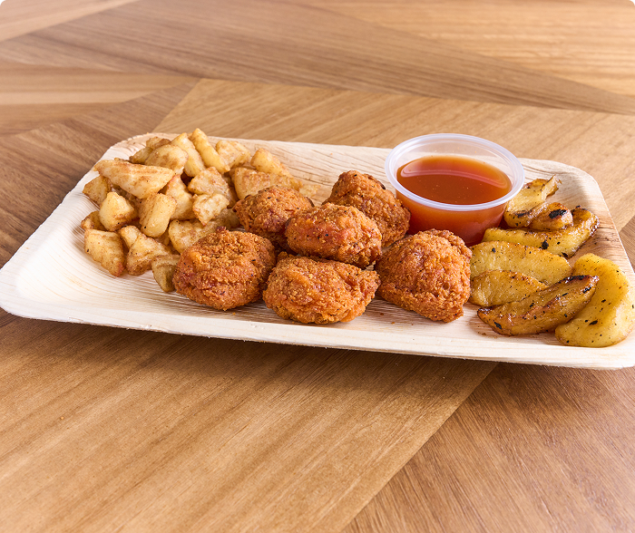 Breaded beef bites on a plate with fried potatoes and a ramekin of dipping sauce on the side 