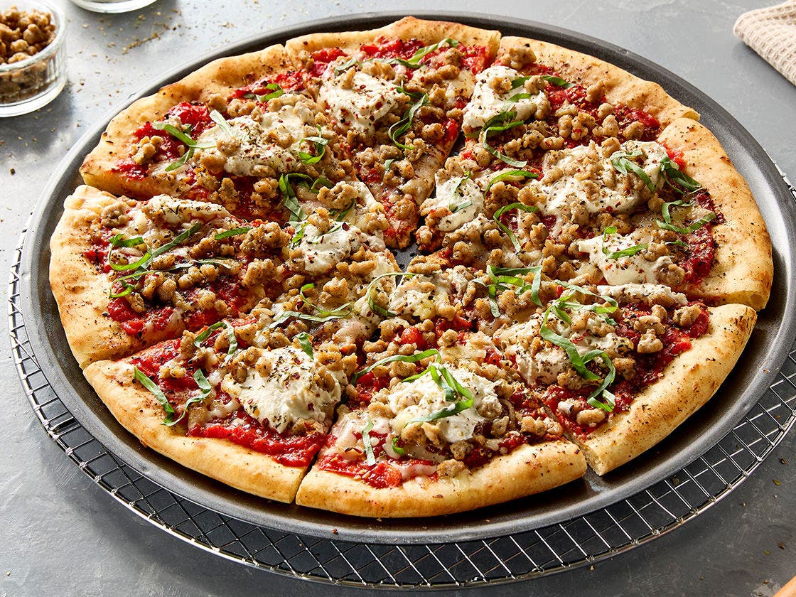 Pizza with Hillshire Farm® Old World Specialties® Italian-Style Sausage and ricotta cheese on a rustic crust, topped with sliced basil and Italian seasoning