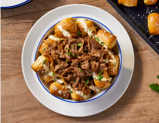 Plated bowl with pretzels, beef slices and white aioli sauce