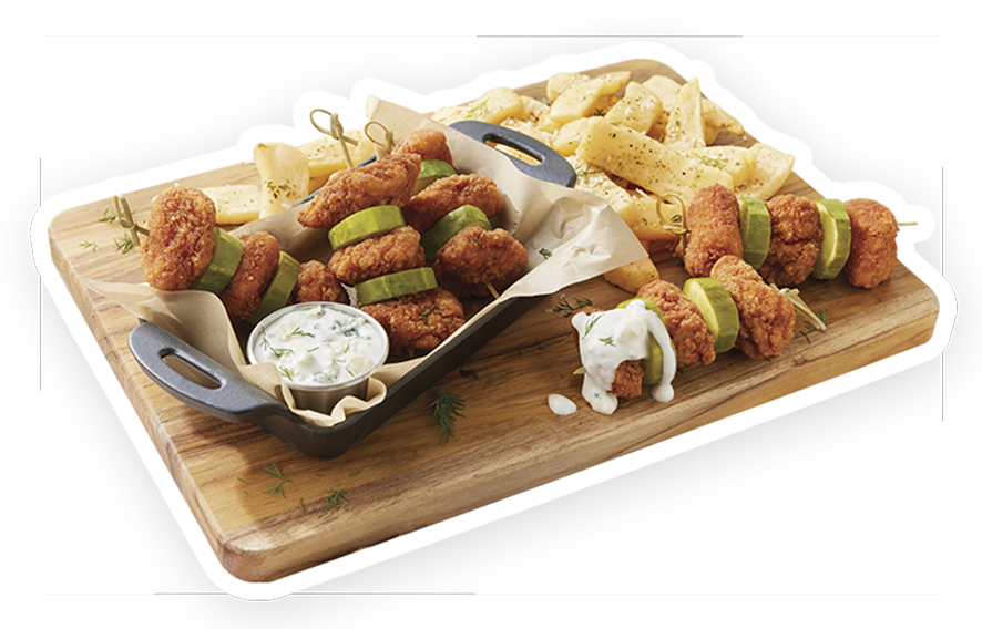 A wooden board featuring skewers of spicy chicken breast chunks and pickles with fries