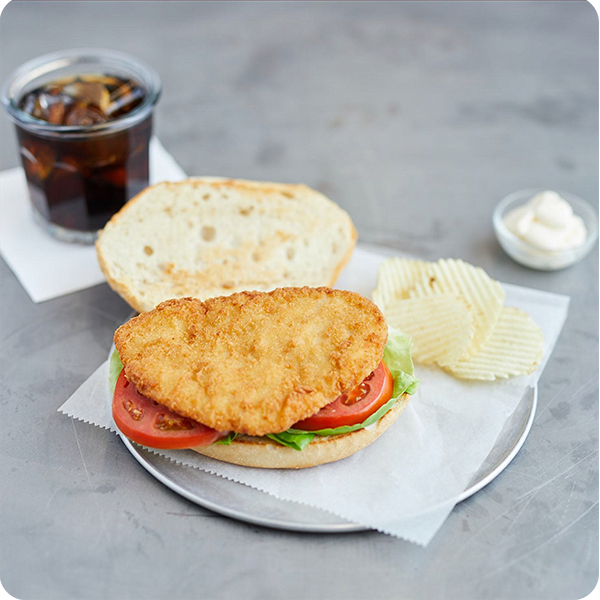 Crispy chicken breast sandwich with lettuce and tomato, served with potato chips.