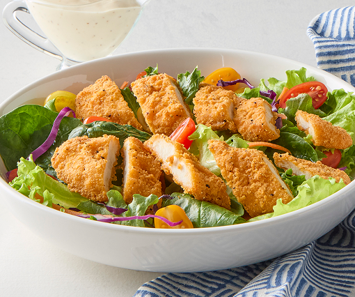 Sliced chicken tenders on chopped salad