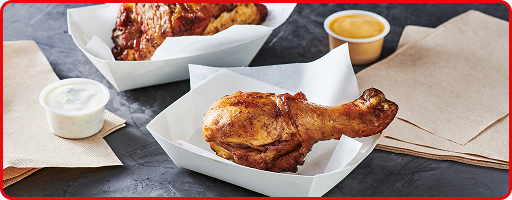 Bone-in chicken wing in a basket with a side of sauce 