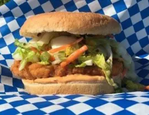 Breaded chicken filet in a hamburger bun stuffed with lettuce, grated carrots and sauce 