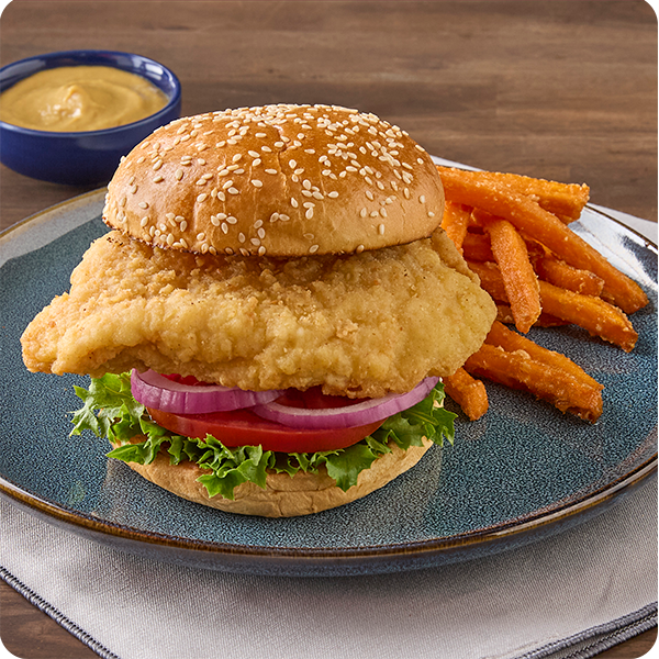 Crispy chicken breast sandwich with lettuce, tomato, and onion, served with fries.