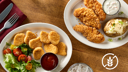 Two plated meals with gluten free chicken nuggets and salad on one plate, and gluten free crispy chicken tenders with a baked potato and dip on another