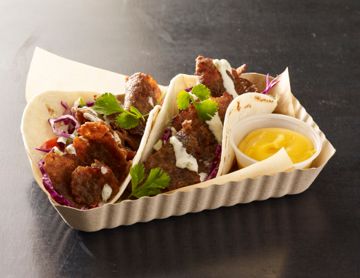 Two flour tortillas stuffed with sliced beef, coleslaw, ranch sauce, cilantro and sauce on the side  