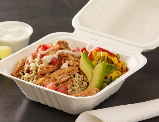 Grilled fajita strips over grains with tomatoes, corn, bell peppers and cilantro sour cream sauce in a to-go container 