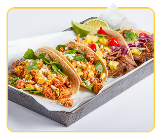 A variety of chicken and beef soft tacos on parchment in a serving tray