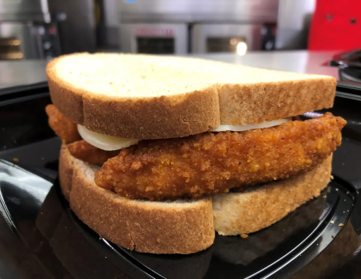 Breaded chicken tenders topped with sliced cheese and blue cheese dressing between slices of thick white bread 