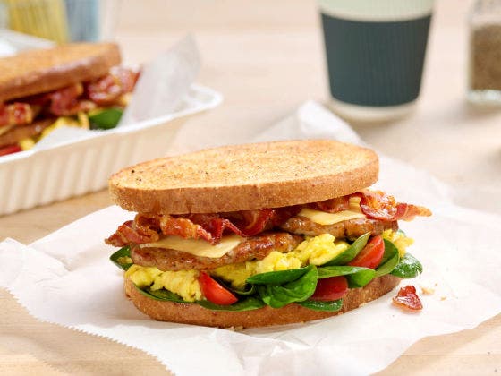 Brunchhouse Breakfast Sandwich Recipe with bacon, pork sausage, scrambled egg, smoked Gouda with grape tomatoes and baby spinach.