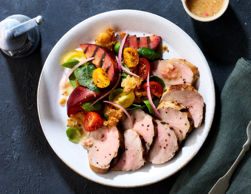 Pork tenderloin on a bread salad with fried croutons, tomatoes, shallots, spinach, basil and grilled plums