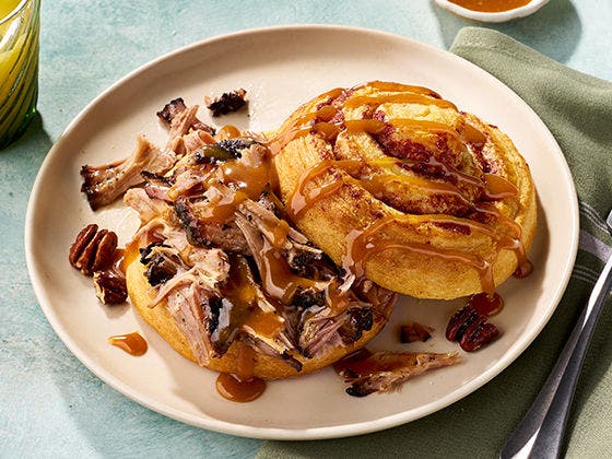 Pulled pork between layers of sticky bun topped with pecans and caramel swirl