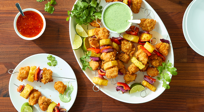 Chicken and pineapple skewers with bell peppers and red onion, served with dipping sauces on the side