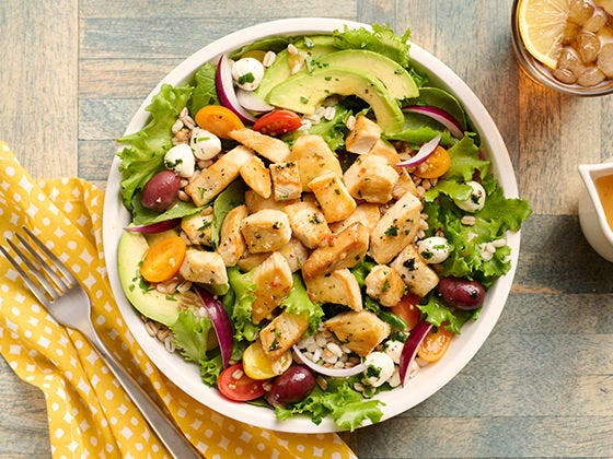 Bowl of farro, leafy greens, Diced Chicken with a side of italian dressing