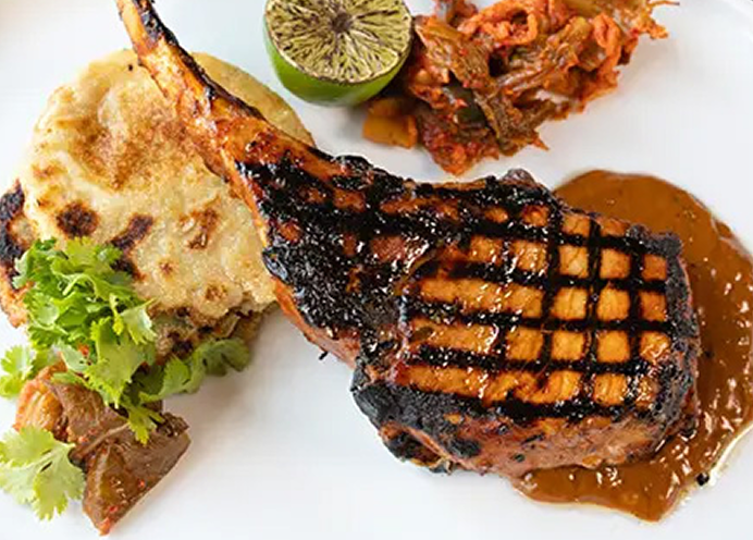 Bone-in pork loin cooked on bed of sauce