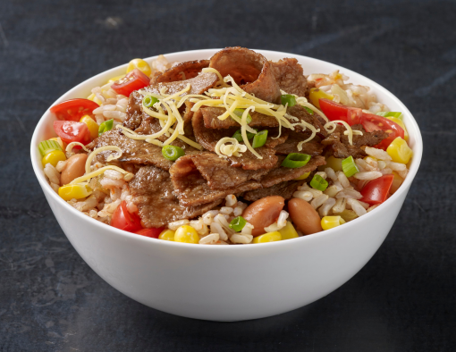 A bowl with sliced beef over rice, pinto beans and tri-colored pepper blend, topped with shredded cheese 