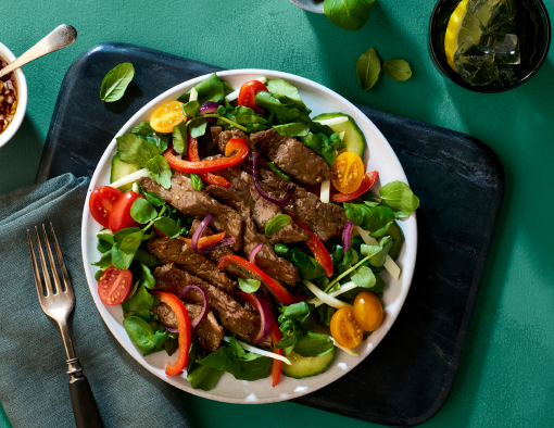 Vietnamese Shaking Beef Salad served over fresh salad of watercress, cherry tomatoes and bell peppers
