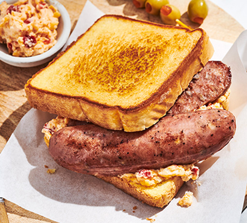 Grilled sausage sandwich with pimento cheese on Texas toast, served on a wooden board
