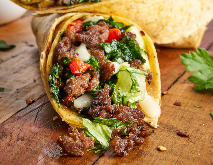 Direct view of an open-ended steak wrap with roasted peppers and herb chimichurri showing   