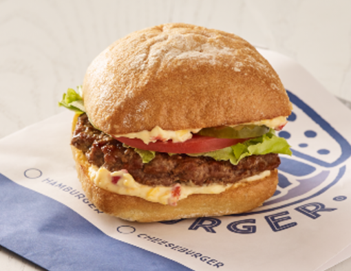 Grilled beef burger topped with pimento cheese, lettuce and tomato on a whole grain bun 