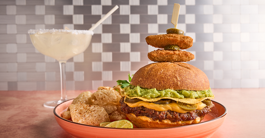 A burger with cheese, jalapeños, guacamole, and a skewer of fried jalapeños, served with pork rinds